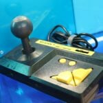 A display case with a game controller and a piece of cheese