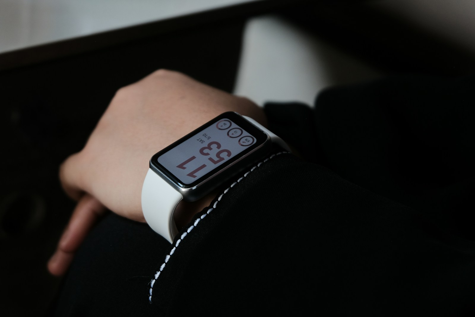 A person wearing a smartwatch with white band.