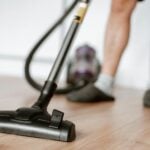 A person uses a vacuum cleaner on a wooden floor for effective cleaning.