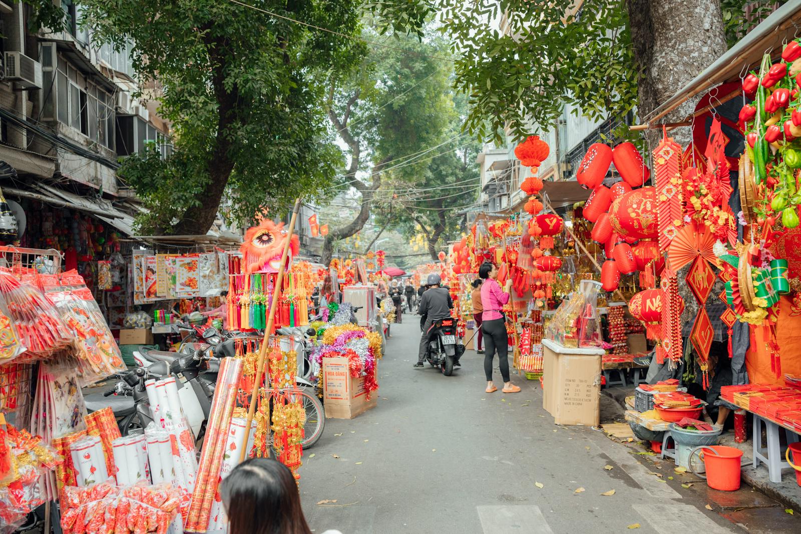 Colorful street market with Chinese New Year decorations and shoppers, creating a festive atmosphere.