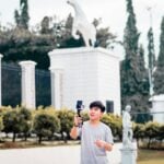 a man holding a microphone in front of a statue