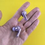 A hand holding a pair of silver ear buds