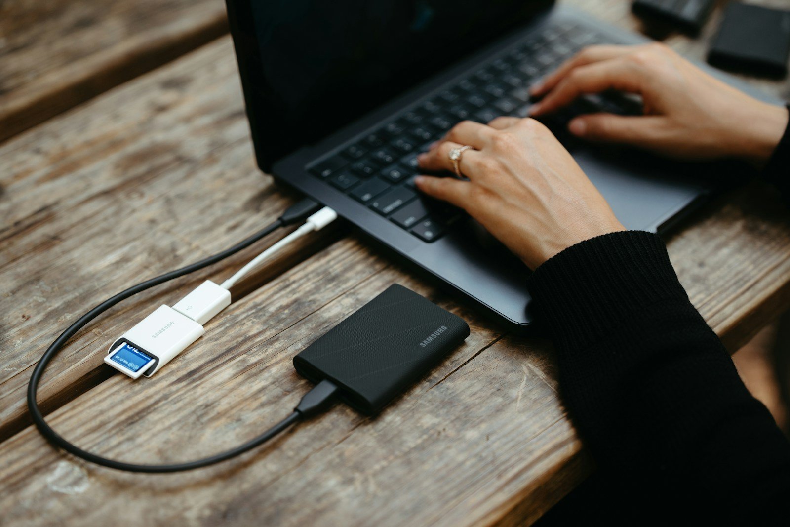 Hands typing on laptop connected to external hard drive.