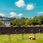 a lawn mower parked in front of a stone wall