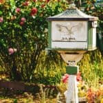 white and green US Mail pedestal mailbox near flowers