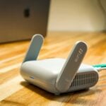 A wireless router sits on a wooden table.