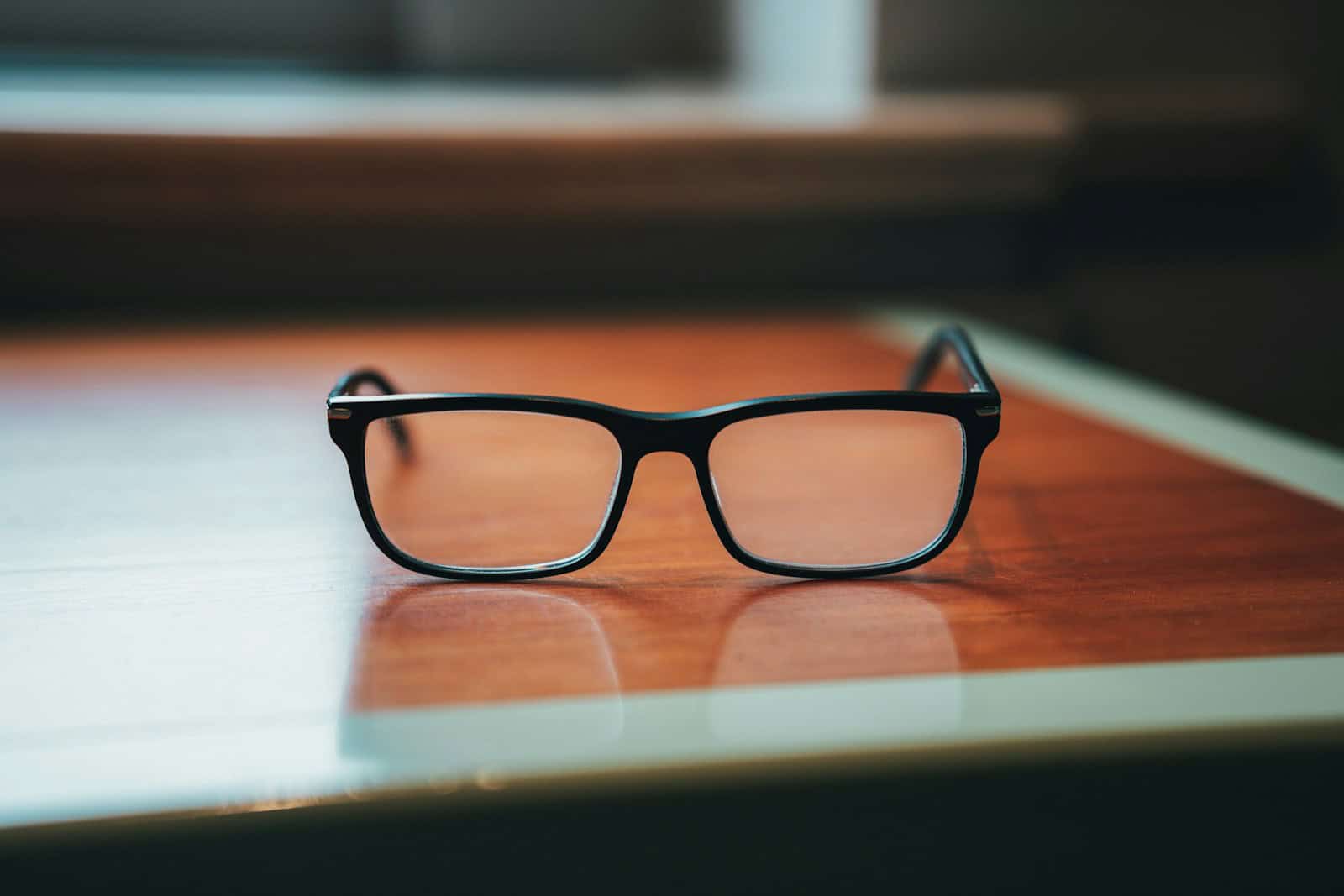 a pair of black glasses on a wooden surface