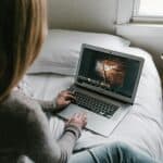 woman using gray laptop on bed