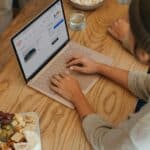 Person sitting on a table clicking on their Surface laptop