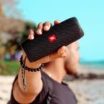 a man holding a black speaker in his hand