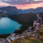 man looking on mountain sitting on rock