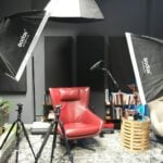 a photo studio with a red chair and umbrella