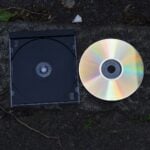 A cd and its case are on a stone surface.