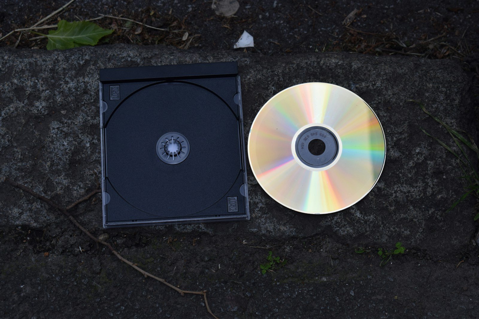 A cd and its case are on a stone surface.