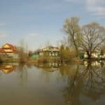 Houses reflect in still water.