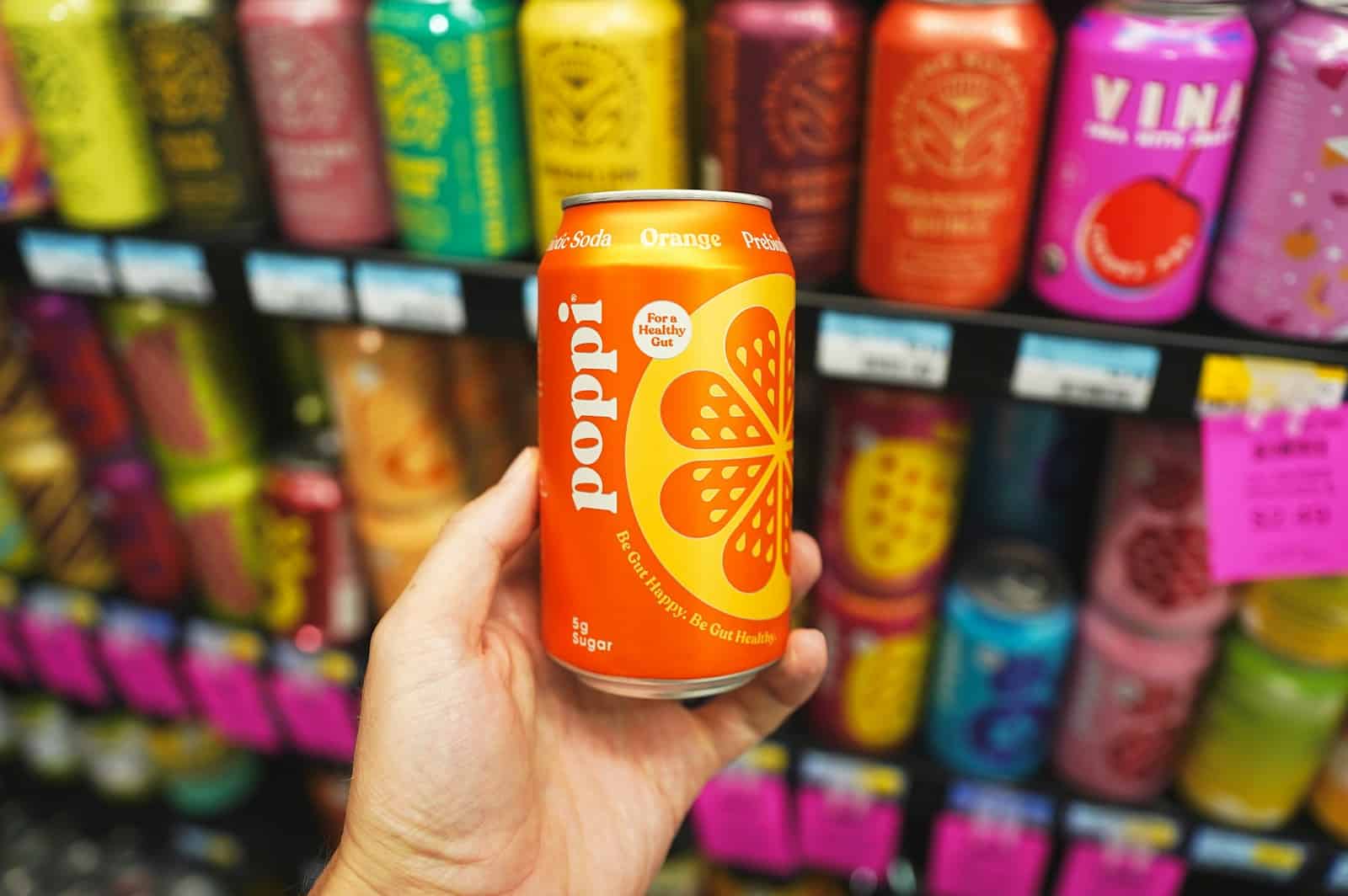 A hand holding a can of orange soda